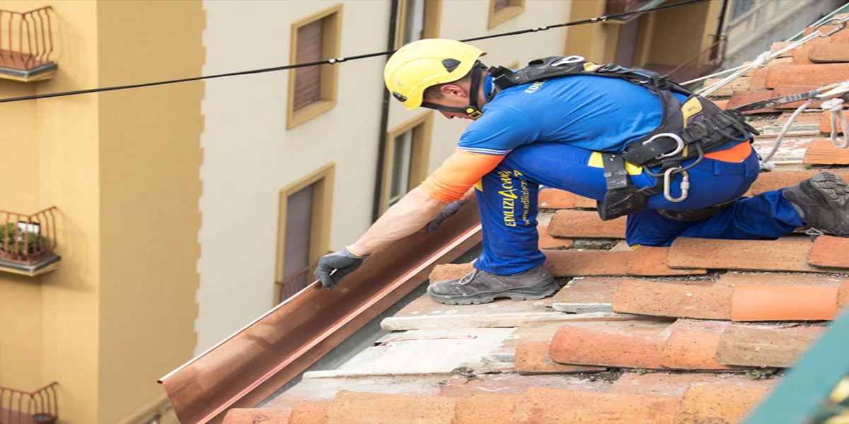 Operario instalando un canalón en el techo de un edificio para mejorar su sistema de drenaje y evitar filtraciones.