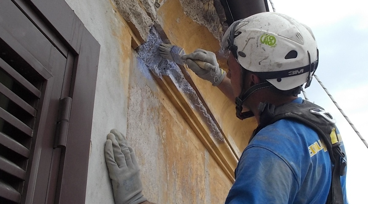 Primer plano de un trabajador de espaldas durante la impermeabilización de fachadas.