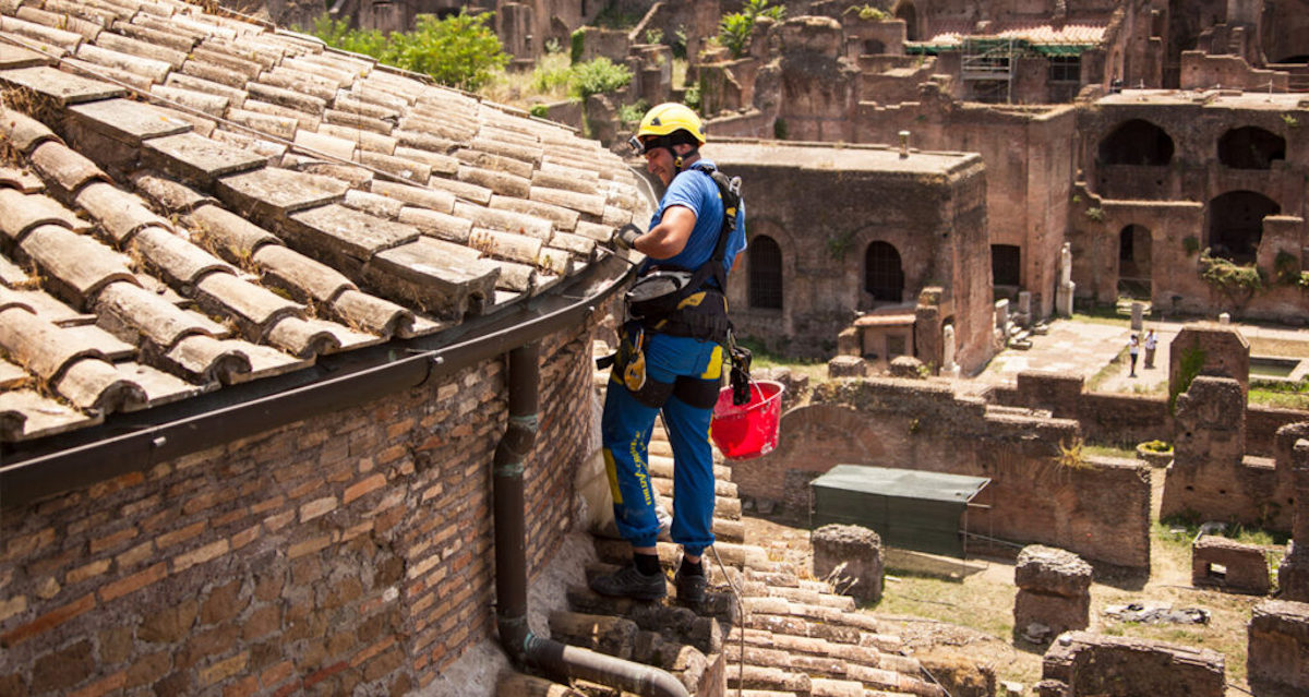 rabajador profesional instalando una canaleta para aguas lluvias en el techo de un edificio histórico, preservando la arquitectura.