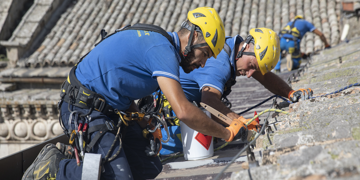 Trabajadores de acrobacia durante una operación de aislantes térmicos para paredes exteriores: abrigo