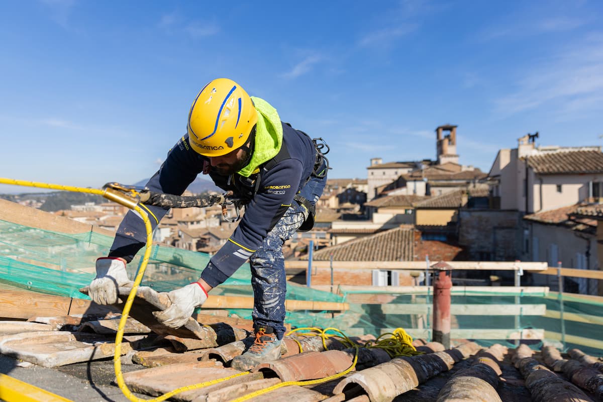 Técnico profesional realizando labores de mantenimiento y reparación estructural en la cubierta de una vivienda.