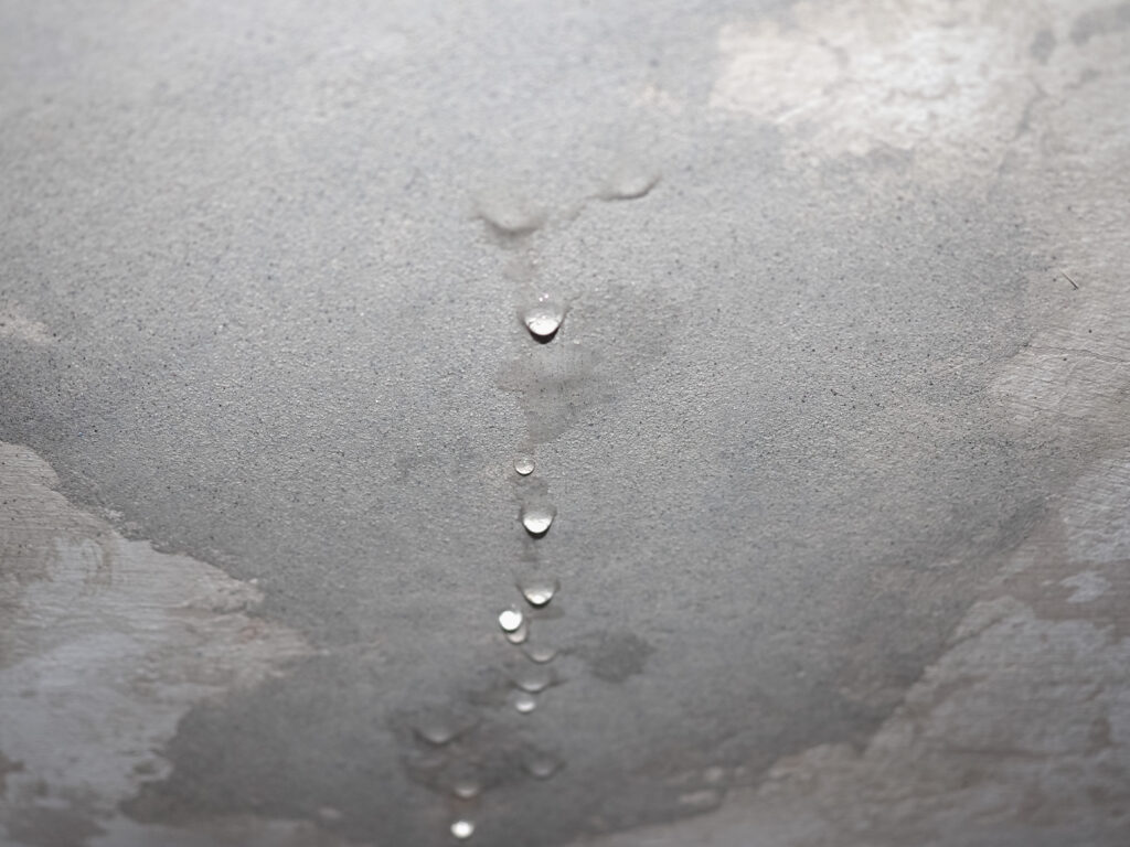 Techo con manchas de humedad y gotas de agua cayendo debido a una filtración.
